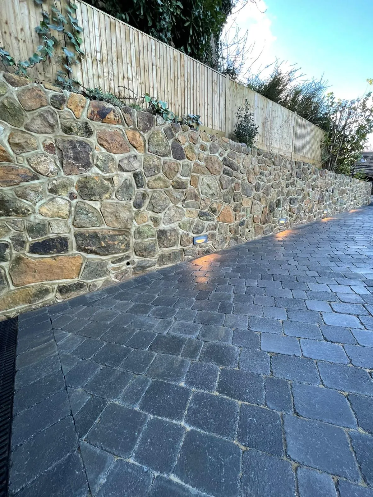 A stone wall next to a brick sidewalk.